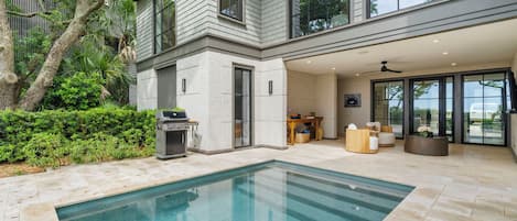 A modern house with a swimming pool, outdoor seating, and a patio area.