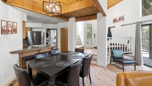 A modern kitchen with a dining area, wooden ceiling beams, and a view of the outdoors. - Shaver Escape – Hot Tub Cabin Retreat with AC + Forest Views (Shaver Lake)