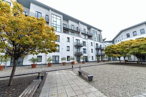 A courtyard with a paved walkway, benches, and potted plants. - Modern apartment for your Belfast stay (Belfast)