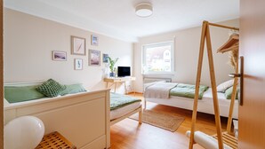 Un dormitorio con cama, escritorio, silla, ventana y radiador.