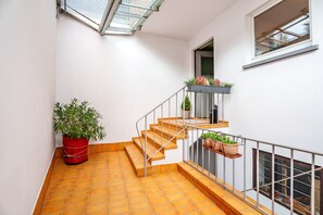 Eine Treppe mit Metallgeländer, Blumentöpfen und einem Fenster.