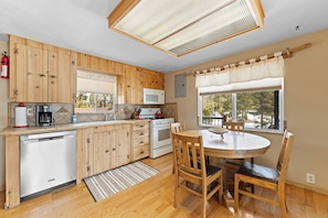 A kitchen with wooden cabinets, a microwave, a dishwasher, and a dining table with chairs.