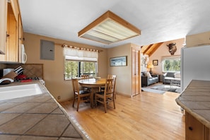 Une cuisine avec une table à manger, des chaises, une fenêtre et un ventilateur de plafond.