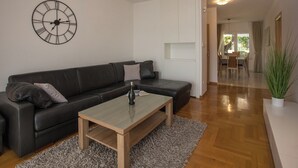 Una sala de estar moderna con un sofá de cuero negro, una mesa de centro de madera y un reloj de pared grande.