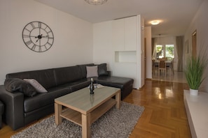 A modern living room with a black leather sofa, a wooden coffee table, and a large wall clock. - Spacious 4-bedroom villa Calluna in wonderful Mastrinka with AC (Mastrinka)