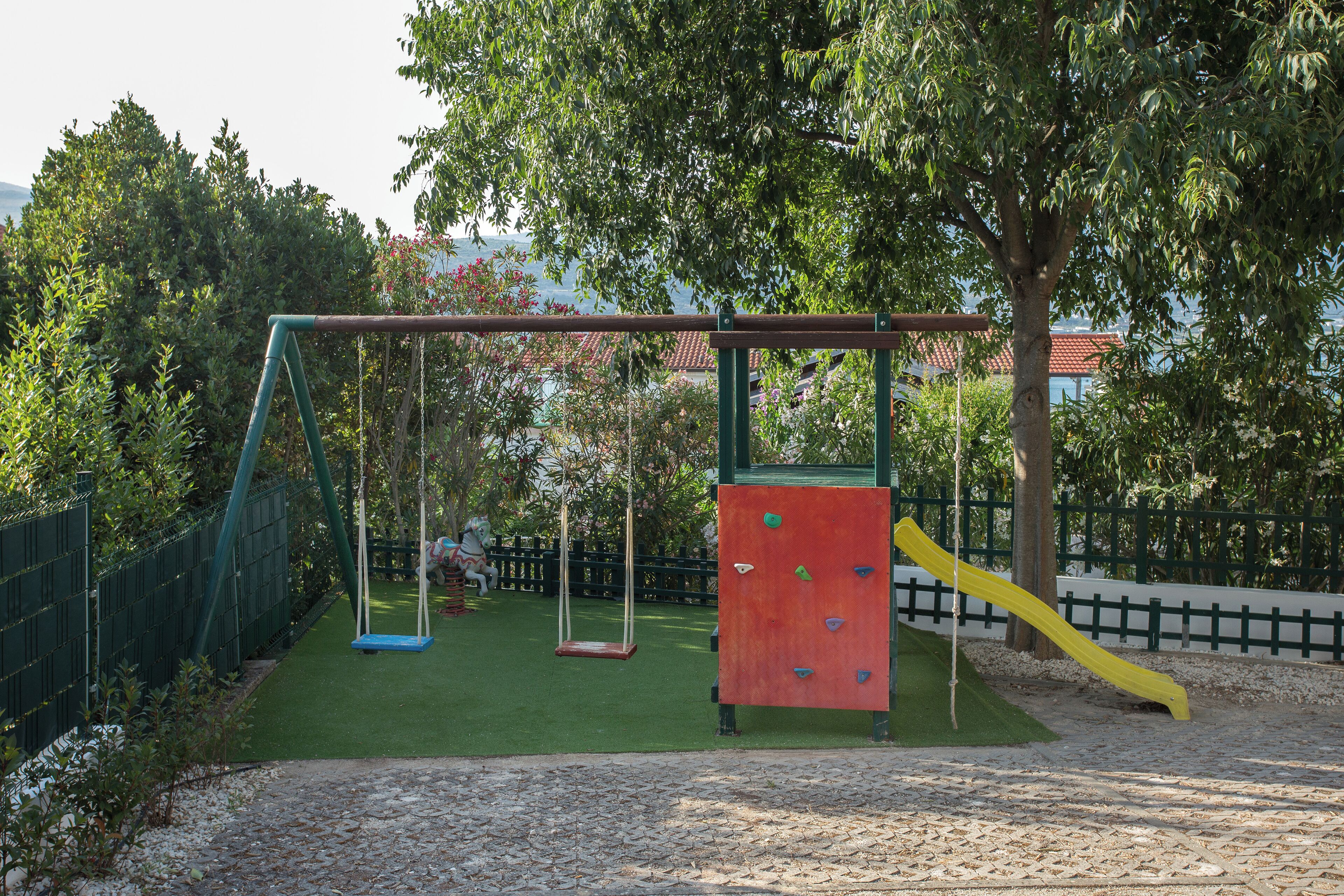 A playground with swings, climbing wall, and slide.