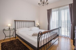A bedroom with a bed, two bedside tables, a chandelier, and a large window with curtains. - Spacious 4-bedroom villa Calluna in wonderful Mastrinka with AC (Mastrinka)