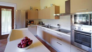 Une cuisine moderne avec des meubles blancs, des appareils en acier inoxydable et un saladier de fruits posé sur le plan de travail.