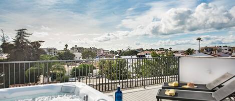 A rooftop terrace with a hot tub, lounge chairs, and a view of the cityscape.