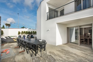 Une terrasse extérieure moderne, aménagée avec une table à manger, des chaises et un barbecue.