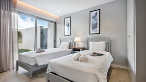 A hotel room with two beds, a large window, and artwork on the walls. - Luxury 6BR Villa Margarida | Pool, Hot Tub & Walk to Albufeira Strip (Albufeira)