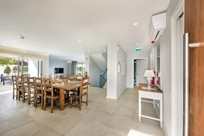 Un grand espace dédié à la salle à manger, avec une table et des chaises en bois, un escalier et une petite table sur laquelle se trouve une lampe.