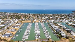 A marina with numerous boats docked in a well-organized layout, surrounded by residential buildings and a clear view of the ocean.