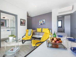 A modern living room with a bed, yellow chairs, a glass coffee table, and a fruit bowl. - Sun, Moon, Star I - Amazing 1 bedroom apartment in Quelfes (Quelfes)