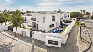A modern white building with a rooftop pool, a covered outdoor seating area, and a paved courtyard. - Villa Violeta - Prime Location, Big-Villa Luxury in the heart of Albufeira (Albufeira)