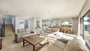 A modern living room with a sofa set, a wooden coffee table, and a dining area with wooden chairs. - Villa Violeta - Prime Location, Big-Villa Luxury in the heart of Albufeira (Albufeira)