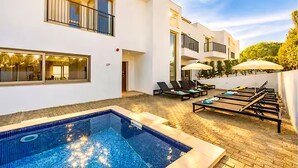 A modern building with a swimming pool, outdoor seating, and a well-lit balcony area. - Villa Violeta - Prime Location, Big-Villa Luxury in the heart of Albufeira (Albufeira)