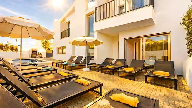 A modern outdoor lounge area with sun loungers, umbrellas, and a pool. - Villa Violeta - Prime Location, Big-Villa Luxury in the heart of Albufeira (Albufeira)