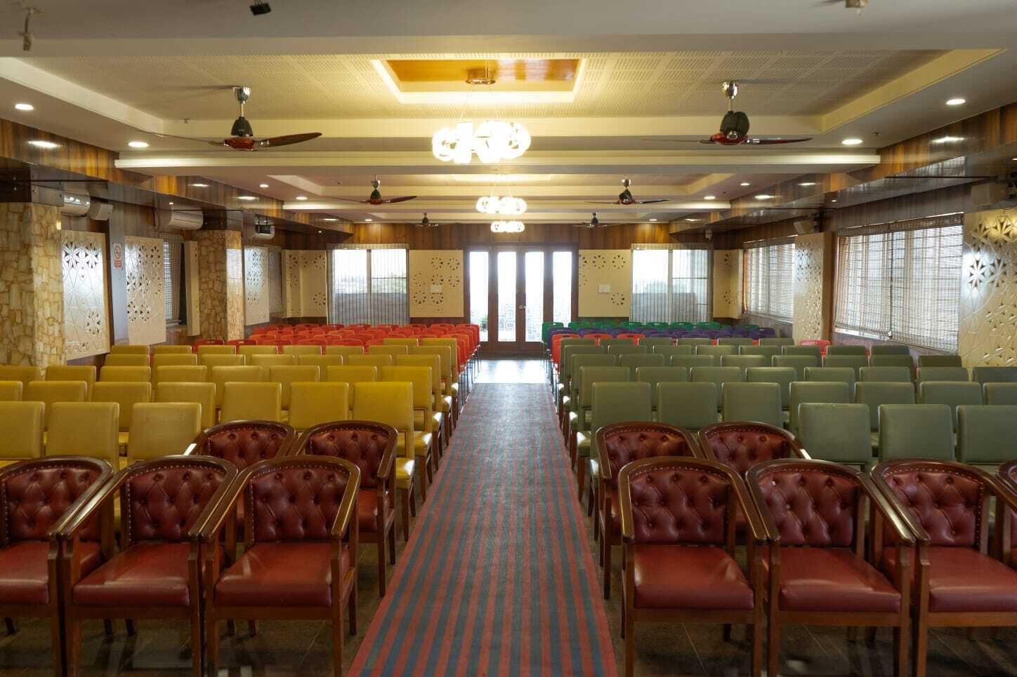 A conference room with rows of chairs, a central aisle, and decorative wall panels.