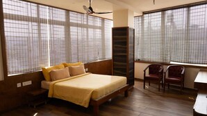 A bedroom with a bed, a desk, and two chairs. - Hotel Grand Inn Jamkhandi (Jamkhandi)