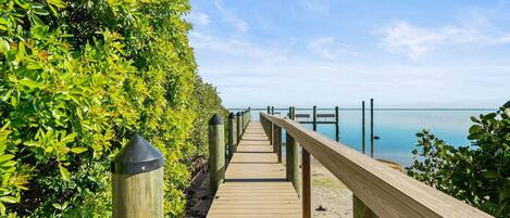 A wooden boardwalk leading to a pier with a clear view of the water.