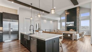 Una cocina moderna con una isla grande, electrodomésticos de acero inoxidable e iluminación colgante.