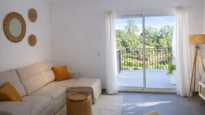 A living room with a beige sofa, a round wooden side table, and a view of a balcony with a railing and greenery outside. - Ap2147 in Denia With 2 Bedrooms and 1 Bathrooms (Denia)