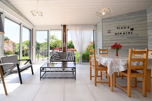 A modern patio with a sofa, chairs, a table, and a view of greenery.