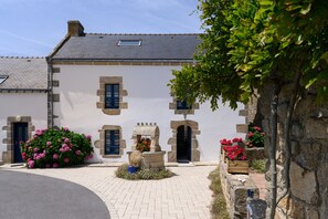 A building with stone walls, a tiled roof, and multiple doors and windows.