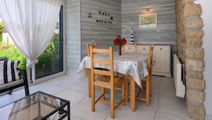 A dining area with a table set for four, a chair with a striped pillow, a vase with red flowers, and a wall with nautical-themed decor. - The Grand Cottage, 400 m from the Beach, Sleeps 11 (Erdeven)