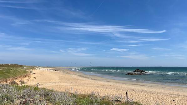 A beach with a sandy shore, waves, and a clear sky.
