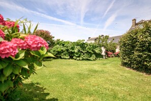 A well-maintained garden with a lawn, hedges, and flowering plants.
