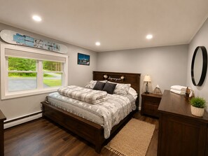 A bedroom with a bed, bedside table, lamp, and a view of the outdoors through a window. - Lovely 4-bedroom Stratton - Mt. Snow Getaway (Wardsboro)