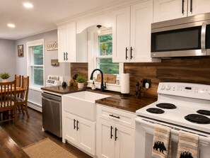 A modern kitchen with white cabinetry, a stainless steel range, a built-in microwave, and a window with a view of greenery. - Lovely 4-bedroom Stratton - Mt. Snow Getaway (Wardsboro)