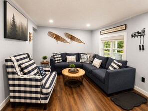 A living room with a checkered sofa, a round coffee table, and a wall-mounted hammock. - Lovely 4-bedroom Stratton - Mt. Snow Getaway (Wardsboro)
