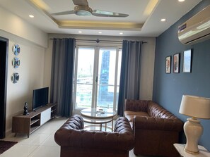 Ein Wohnzimmer mit einer Couch, einem Fernseher, einem Couchtisch und einem Deckenventilator.