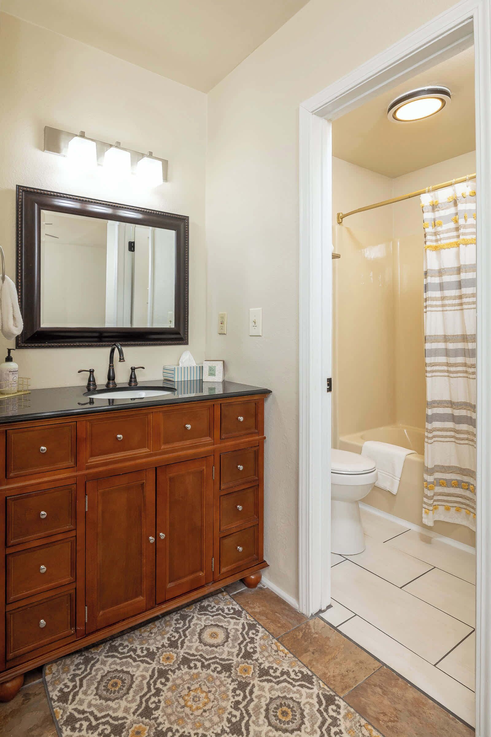 A bathroom with a wooden vanity, a large mirror, a sink, and a shower area.