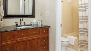 A bathroom with a wooden vanity, a large mirror, a sink, and a shower area.