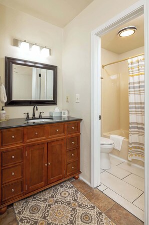 A bathroom with a wooden vanity, a large mirror, a sink, and a shower area.