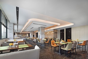 Un restaurant moderne doté de plusieurs espaces de restauration, d’un bar et offrant une vue sur la ville.