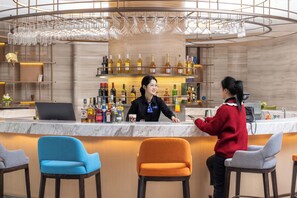 Een bar met een barman, een klant en een assortiment drankflessen.