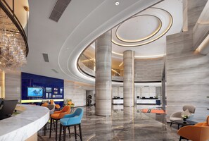 Un hall d’hôtel moderne doté d’un plafond incurvé, d’un sol en marbre et d’un comptoir d’accueil équipé d’un ordinateur.