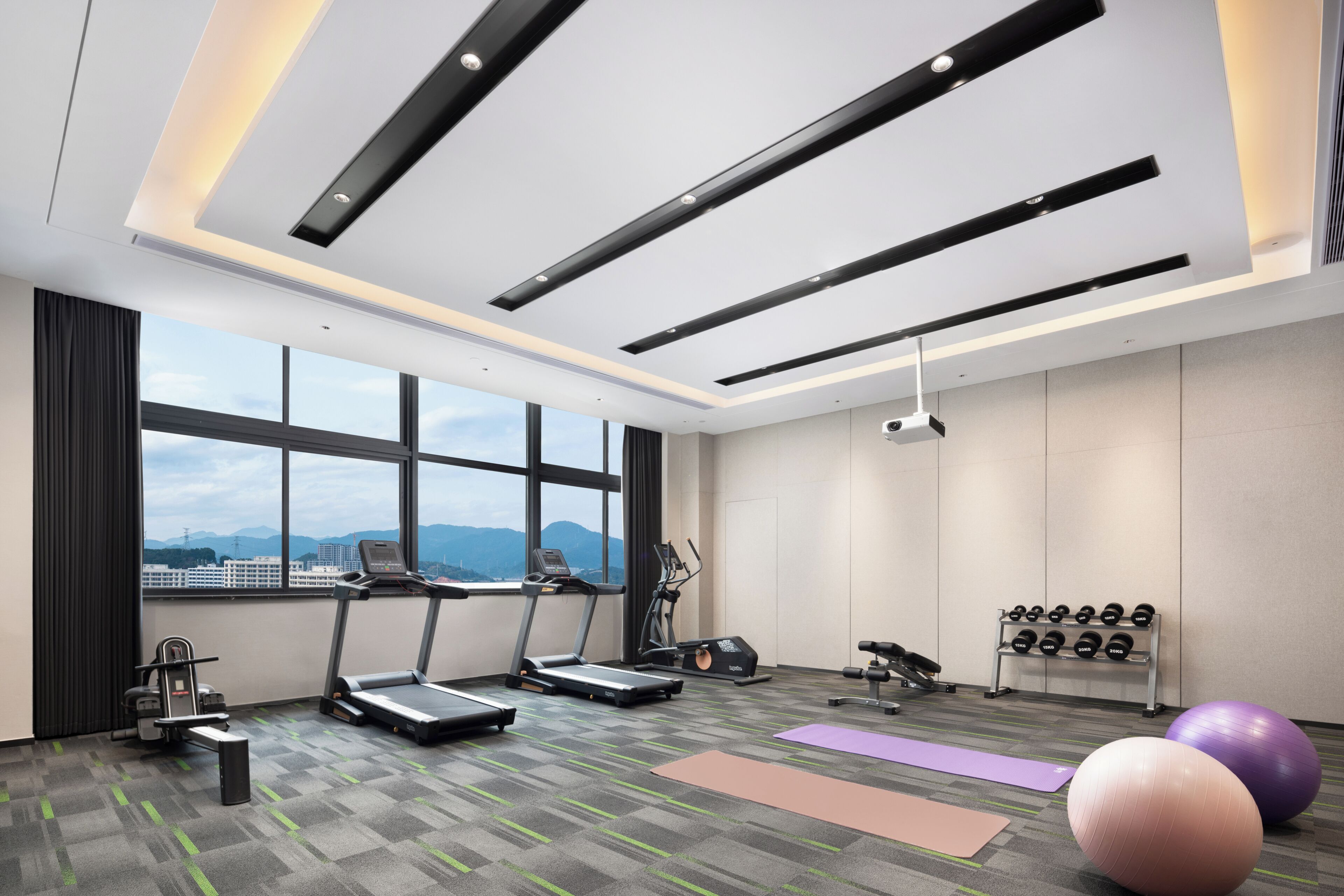 Un gimnasio moderno con cintas de correr, pelotas de ejercicio y mancuernas.