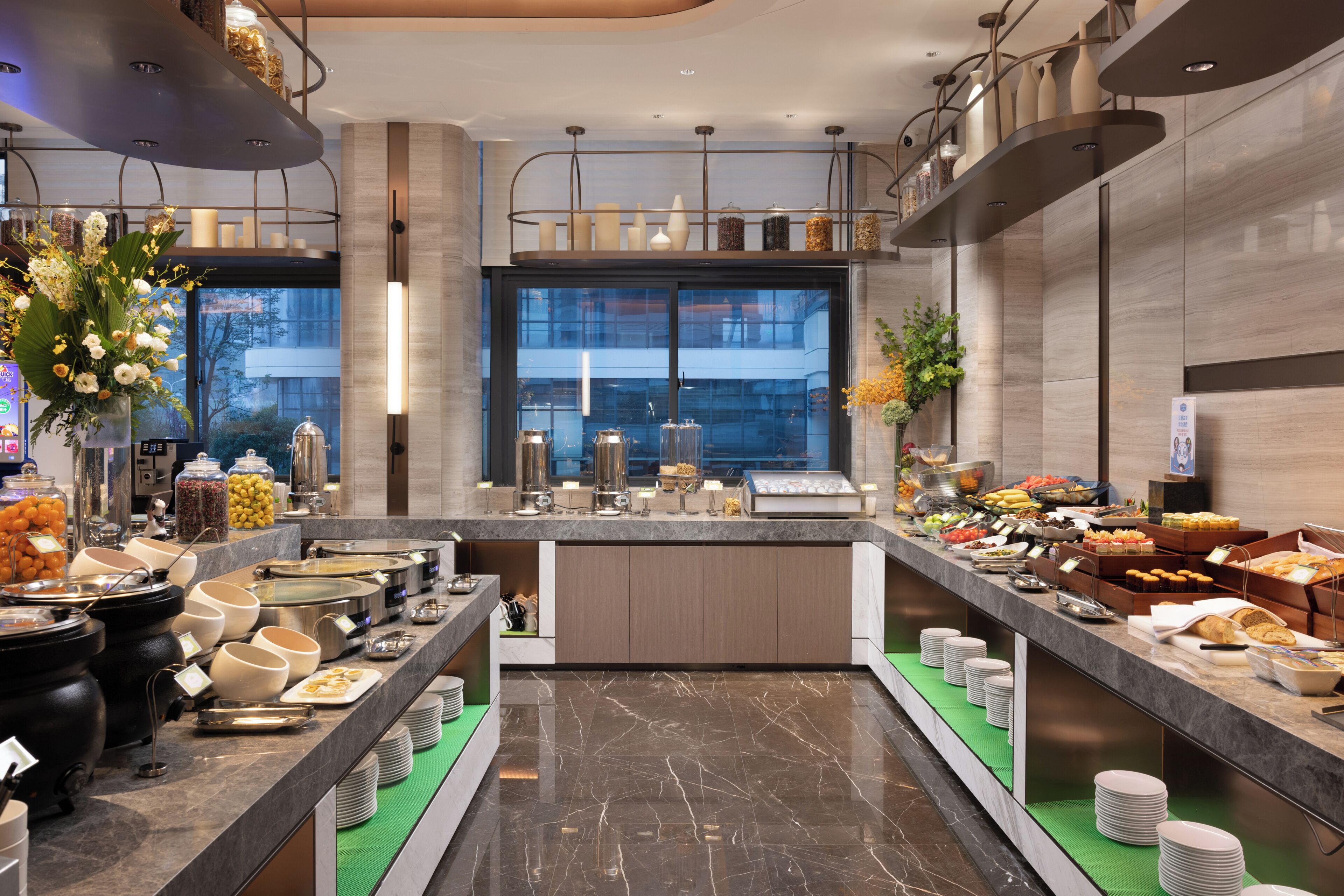 Un moderno montaje tipo buffet con diversas opciones de comida, un ventanal grande y un diseño limpio y contemporáneo.