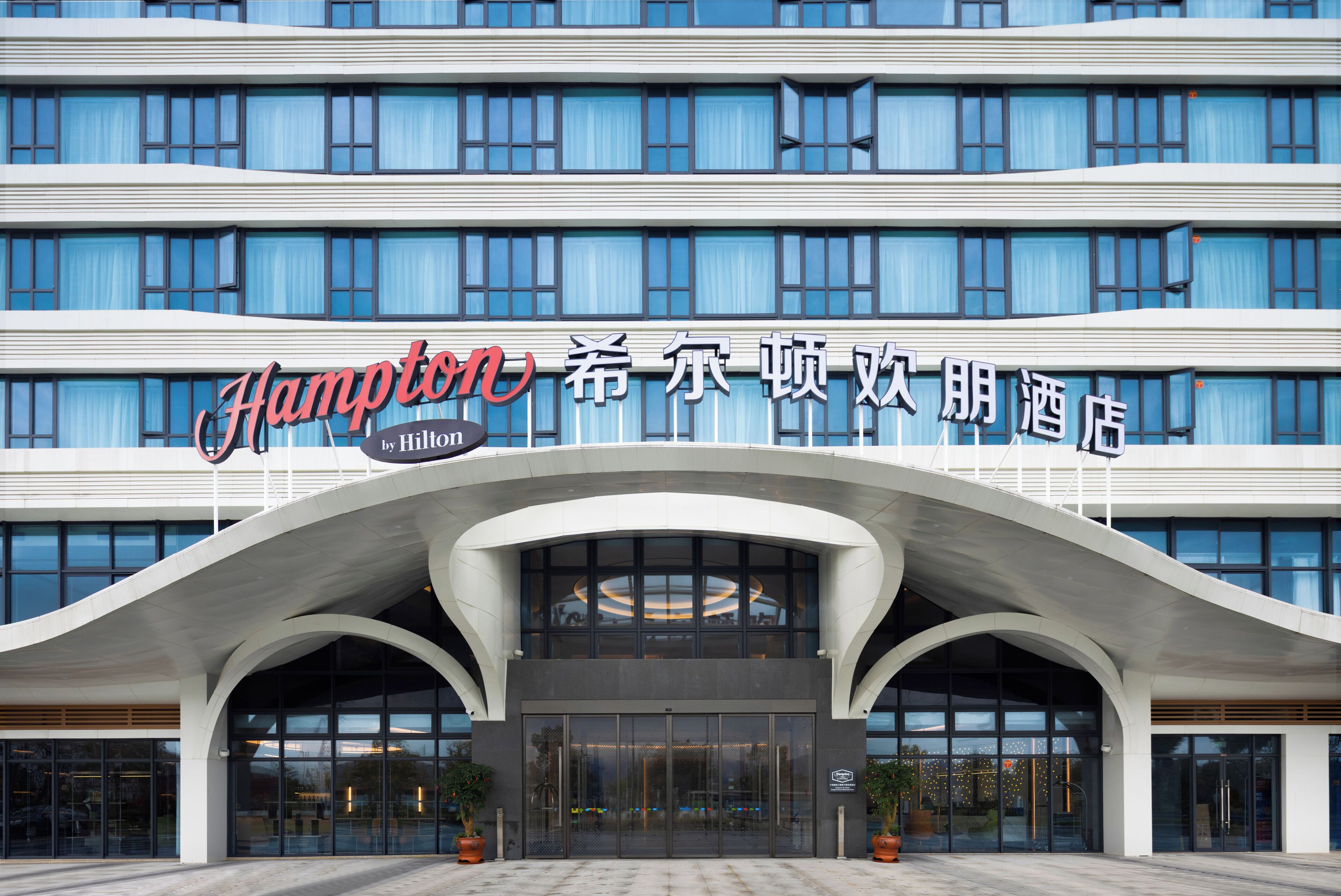 A hotel with a modern design, featuring a prominent arched entrance and large windows.