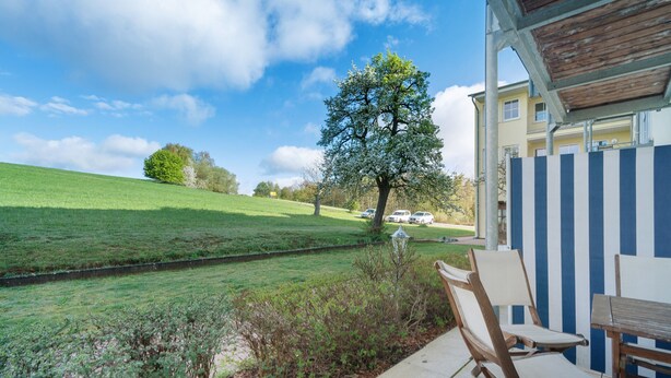A patio with outdoor furniture, a view of a green field, and a tree. - Dog-Friendly Apartment H1 005 (Spalt)