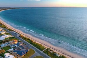 An aerial view of a coastal area with a beach, houses, and a road. - Waikiki Coastal Retreat | Walk to Beach | Pet Friendly (Waikiki)