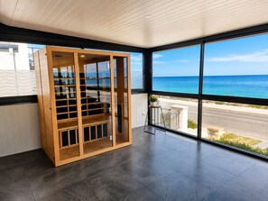 A room with a large window, a wooden cabinet, and a view of the sea. - Waikiki Coastal Retreat | Walk to Beach | Pet Friendly (Waikiki)