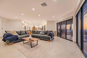 A modern living room with a sectional sofa, a coffee table, and a view through large sliding glass doors. - Waikiki Coastal Retreat | Walk to Beach | Pet Friendly (Waikiki)