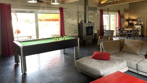 Una mesa de billar en una sala de estar con un sofá y un cojín rojo.